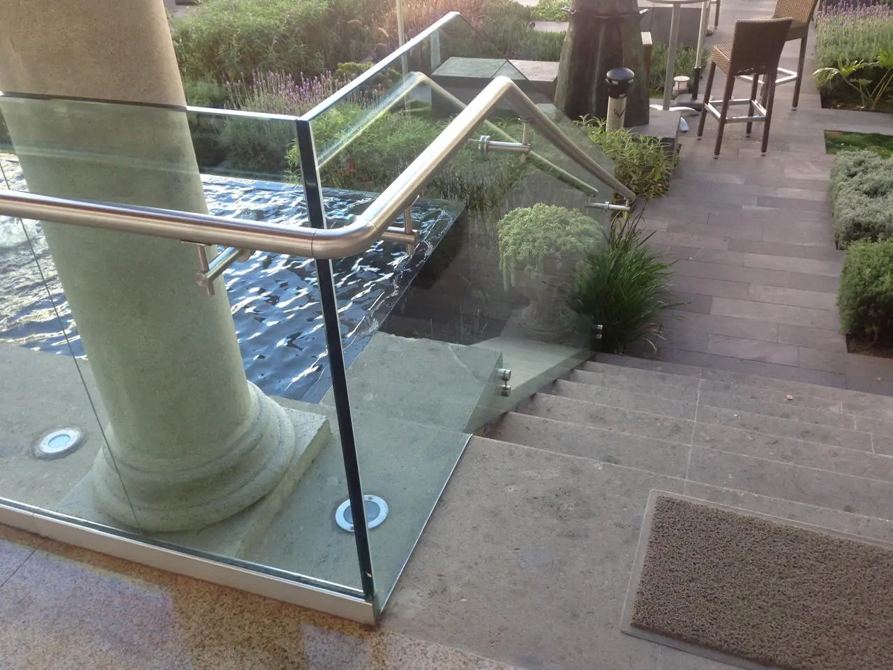 Barandal de cristal templado con pasamanos de acero inoxidable y conectores punto fijación instalado por Vantania en escaleras exteriores de CDMX.