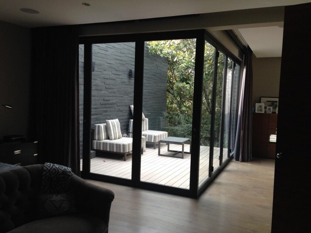 Cancelería de aluminio y cristal templado en CDMX con puertas corredizas en esquina para terraza residencial.