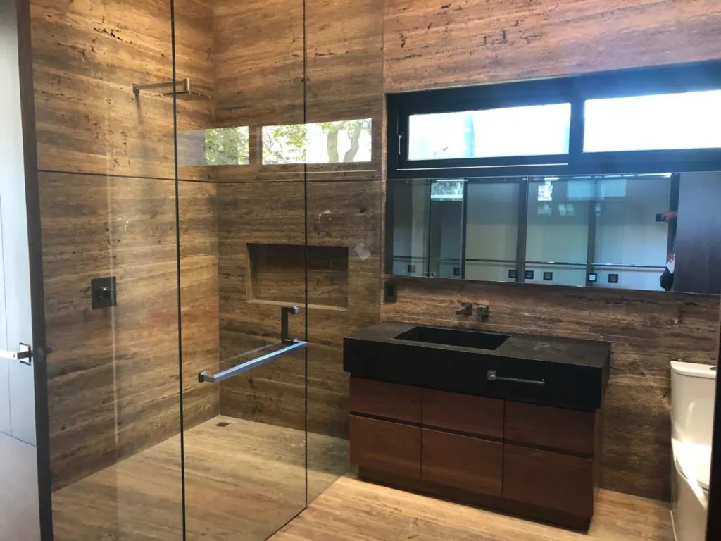 Cancel de baño en cristal templado claro con jadera toallero y herrajes de acero inoxidable instalado por Vantania en CDMX.