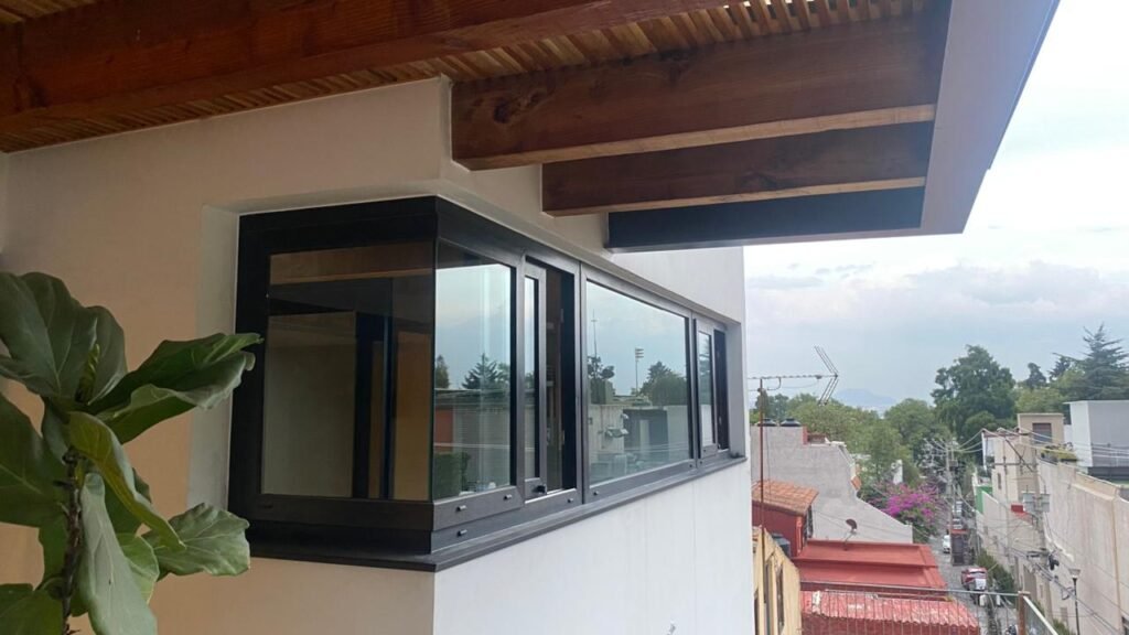 Ventanas antiruido de aluminio negro con sellado hermético instaladas en fachada residencial por Vantania en CDMX.